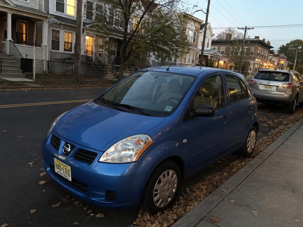 Blue economy city car parked along a residential city street at dusk